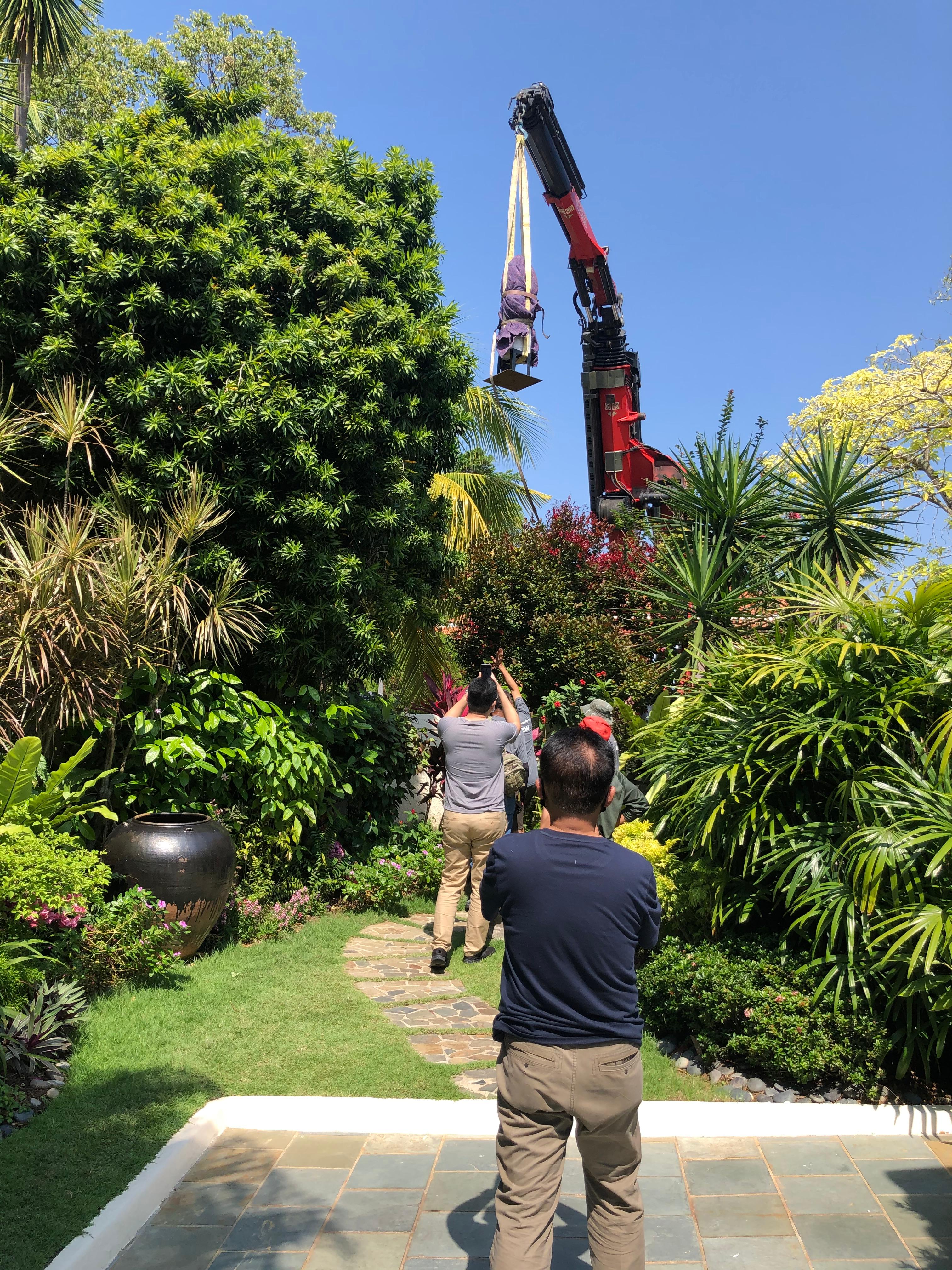 Crane installation of quartz pillar in bungalow garden